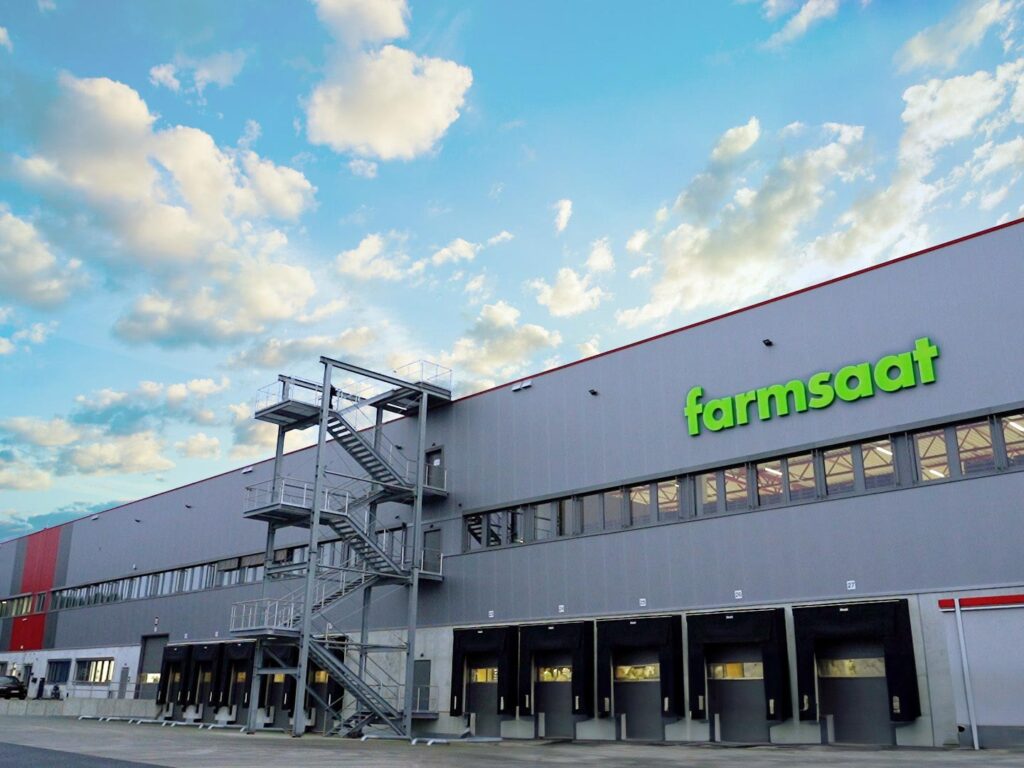 Die große Logistikhalle von außen mit leuchtendem Logo